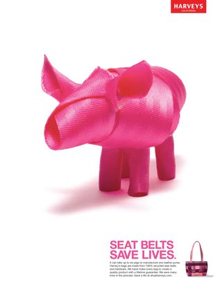 A pink seatbelt fashioned to look like a pig, with the copy 'Seat belts save lives' in the bottom right corner